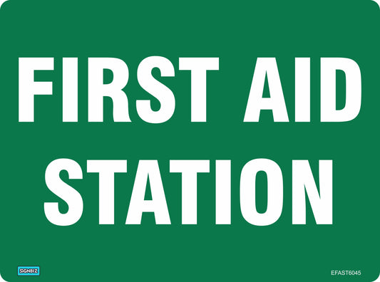 A green Emergency First Aid Station sign features large, all-capital white text reading "FIRST AID STATION," rounded corners, and a small label in the bottom left indicating the location of first aid facilities.