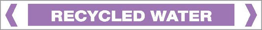 The Pipe Marker - ACID / ALKALI - RECYCLED WATER features a rectangular design with a purple background, white border, bold uppercase "RECYCLED WATER" text, and two white chevrons on each side.